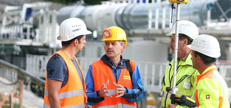 Peter Maile (Zweiter von links) im Gespräch mit Arbeitern auf der Baustelle bei Aichelberg. Auf dem kleinen Foto ist der Diakon