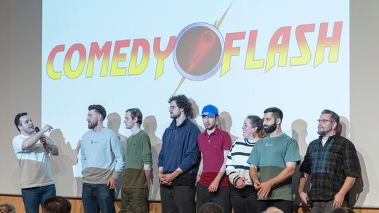 Comedyflash: Der Organisator Dionysis Ghenes (links) mit den sieben Comedians des Abends. Foto: Peter Dietrich