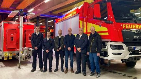 Feuerwehrangehörige und Vertreter der Stadt bei der Übergabe des Tanklöschfahrzeugs und des mobilen Notstromaggregats.  Foto: pr