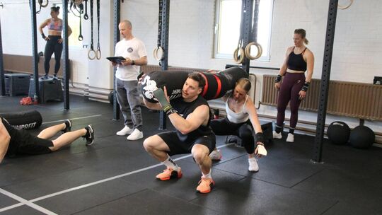 Das gemeinsame Stemmen des 50-Kilo-Sacks funktioniert nur dann so richtig, wenn das Zweier-Team seine Kniebeugen synchron ausfüh Das gemeinsame Stemmen des 50-Kilo-Sacks funktioniert nur dann so richtig, wenn das Zweier-Team seine Kniebeugen synchron ausfüh