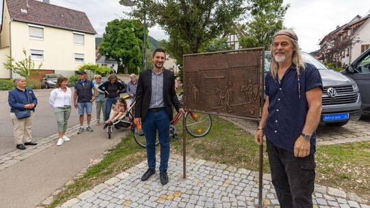 Bürgermeister Jens Fritz (links) und Künstler Winfried Tränkner zeigen dessen frisch enthüllte Bronzetafel, die das Viehwiegen a Bürgermeister Jens Fritz (links) und Künstler Winfried Tränkner zeigen dessen frisch enthüllte Bronzetafel, die das Viehwiegen a