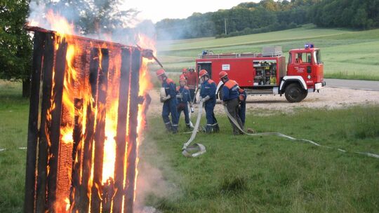 Eine Palette steht in freier Natur in hellen Flammen. Die Kinder und Jugendlichen löschen sie mit vereinten Kräften. Foto: pr Eine Palette steht in freier Natur in hellen Flammen. Die Kinder und Jugendlichen löschen sie mit vereinten Kräften. Foto: pr