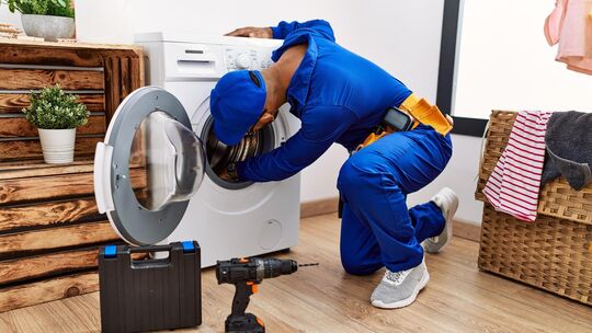 Young arab man wearing technician uniform repairing washing machine at laundry room Young arab man wearing technician uniform repairing washing machine at laundry room