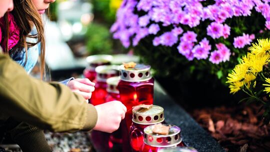 Viele Menschen besuchen die Gräber ihrer Lieben auf Friedhöfen, schmücken die Grabstätten mit Kerzen, Blumen und Bildern und ver