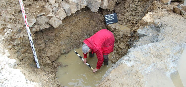Der Göppinger Kreisarchäologe Reinhard Rademacher misst den neu entdeckten Brunnenschacht aus. Foto: Maximilian Haller