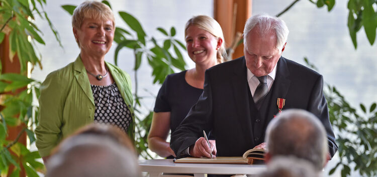 Gert Hauschild trägt sich ins Goldene Gästebuch der Gemeinde ein. Mit ihm freuen sich Staatssekretärin Friedlinde Gurr-Hirsch (l