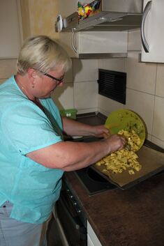 Helga Jauß gibt die mit Öl verfeinerten Kartoffeln auf ein Backblech.Fotos: Helga Wahl
