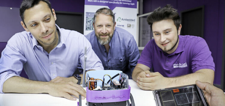 Dr. Tim Ganser (links) und Steffen Kernstock (mitte) zeigen einen Roboter, den der Informatik-Azubi Robert Macht zusammengebaut