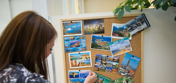 Postkarten , jemand schaut sich Postkarten auf einer Pinnwand an