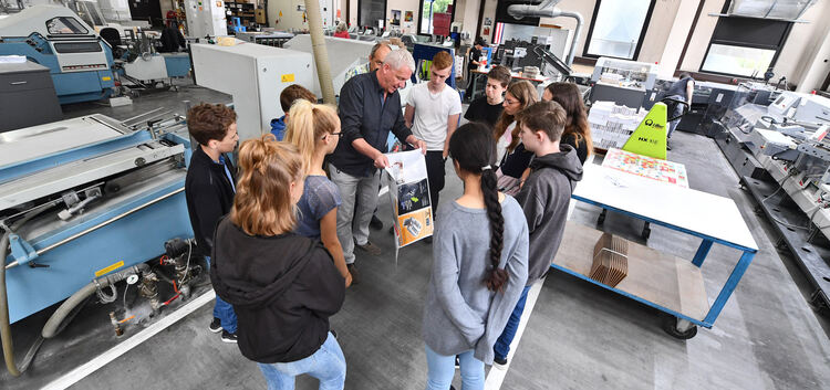 Bruno Panni zeigt Jugendlichen im Rahmen der „Betriebs-Ferien“ Druckmaschinen und deren Erzeugnisse - hier im Bild noch vor der