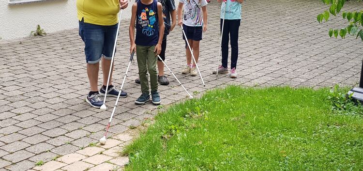 Kinder erfühlen die Welt mit Blindenlangstöcken.