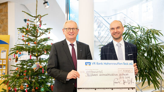 Vor dem Weihnachtsbaum überreichen Bruno Foldenauer (links)und Stefan Gerlach von der VR Bank einen großen Scheck. Unten ist der