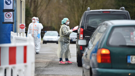 Die Patienten stehen Schlange, um sich eine Probe entnehmen zu lassen. Nur wer sich vor Kurzem im Riskogebiet aufgehalten hat un Die Patienten stehen Schlange, um sich eine Probe entnehmen zu lassen. Nur wer sich vor Kurzem im Riskogebiet aufgehalten hat un