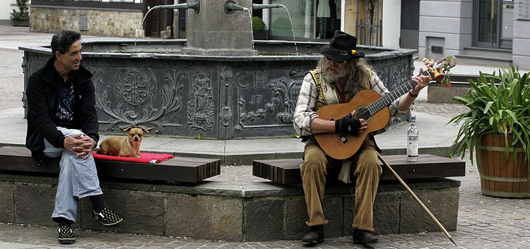 Gerne mit der Gitarre unterwegs: Aki spielt am Kirchheimer Marktbrunnen einem Passanten ein Ständchen. Foto: Jörg Bächle
