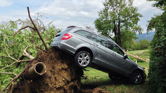 Unwetter enteurzelt Baum und hebt Mercedes hoch