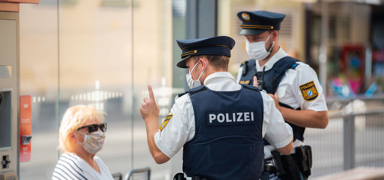 27.08.2020, Bayern, Würzburg: Zwei Polizisten nehmen an einer Tram-Haltestelle von einer Frau nach einem Verstoß gegen die Maske