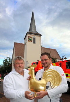 Gerhard (links) und Christian Seyfang präsentieren den Naberner Turmhahn, den sie mit neuem Blattgold überzogen haben. Unten bes