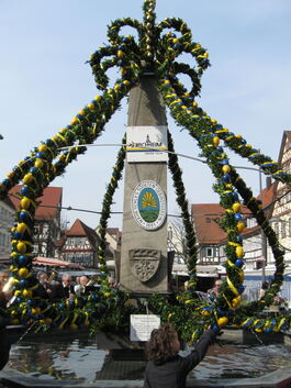 Buchsgirlanden mit blauen und gelben Ostereiern zieren seit Samstag den Kirchheimer Marktbrunnen. Foto: Monika Riemer
