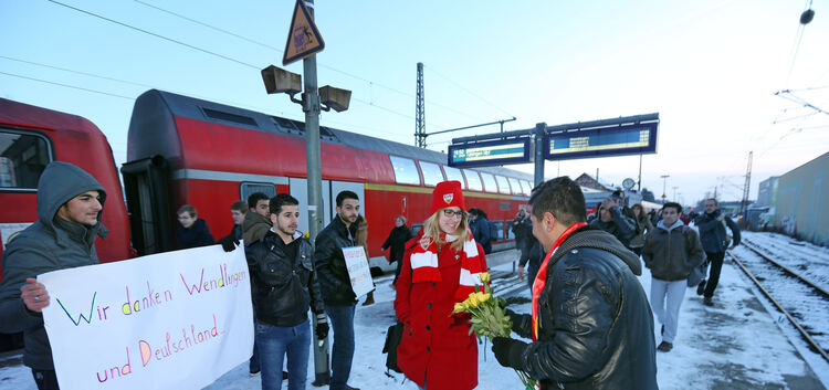 Mit gelben Rosen heißen die Flüchtlinge eine junge Frau am Bahnhof willkommen. Foto: Roberto Bulgrin